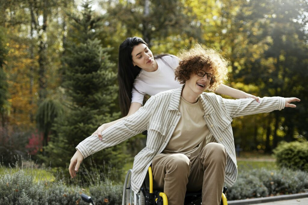 Cheerful guy - a disabled person sits in a wheelchair, in the park.