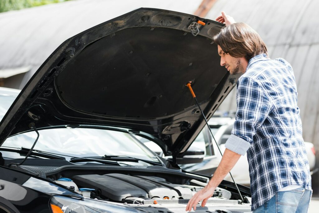 man standing near broken auto with open trunk, car insurance concept